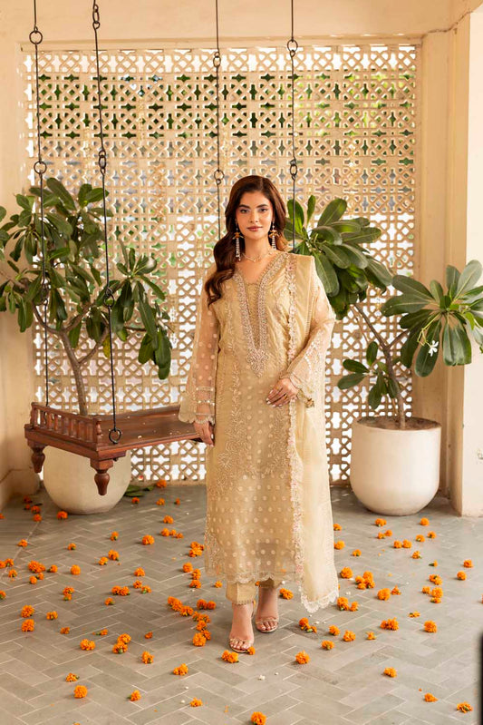 Woman in a beige traditional outfit standing in a decorated indoor setting with plants and decorative elements.