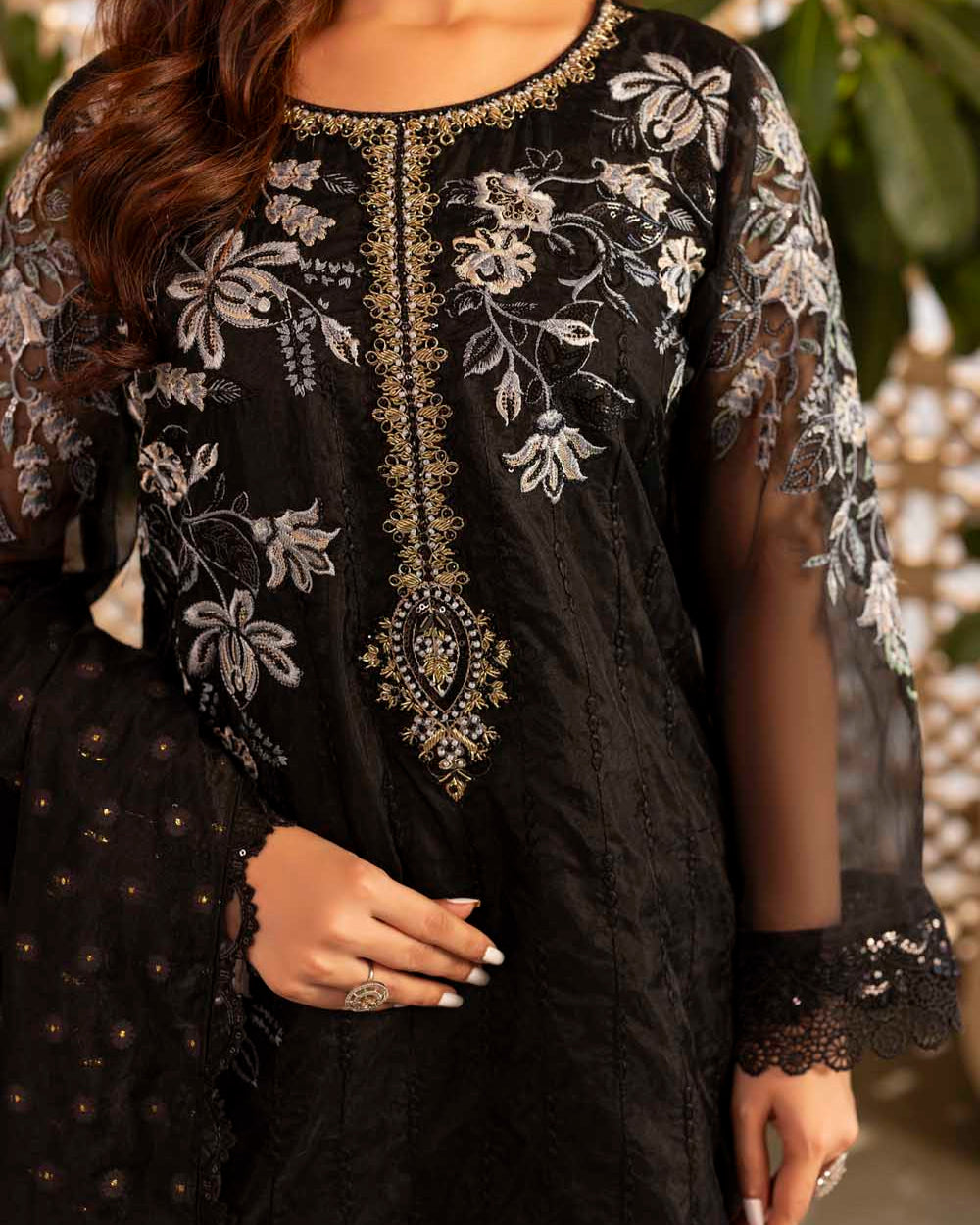 Black embroidered dress with floral patterns worn by a person, blurred background