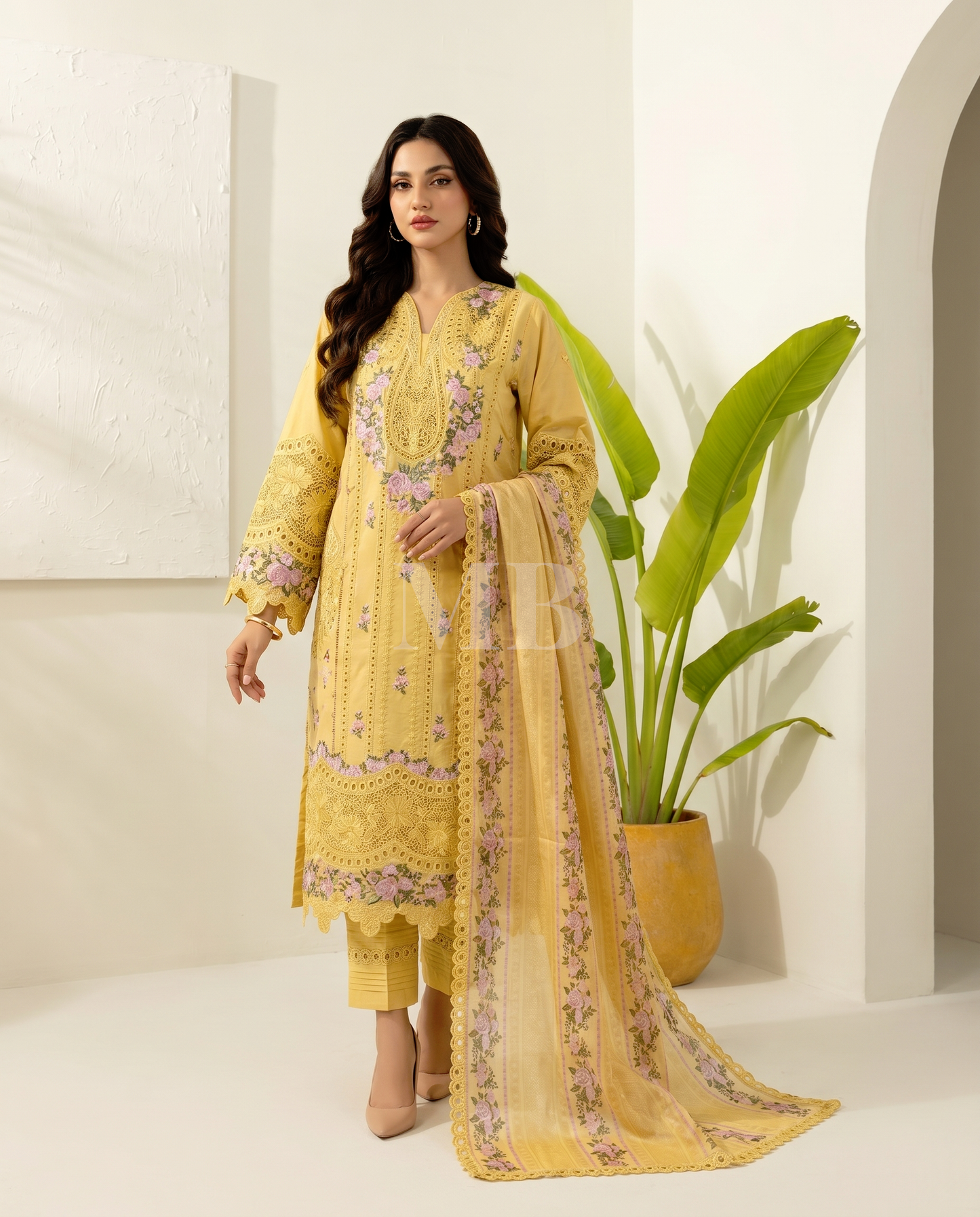 Woman wearing a yellow embroidered traditional outfit with a plant in the background