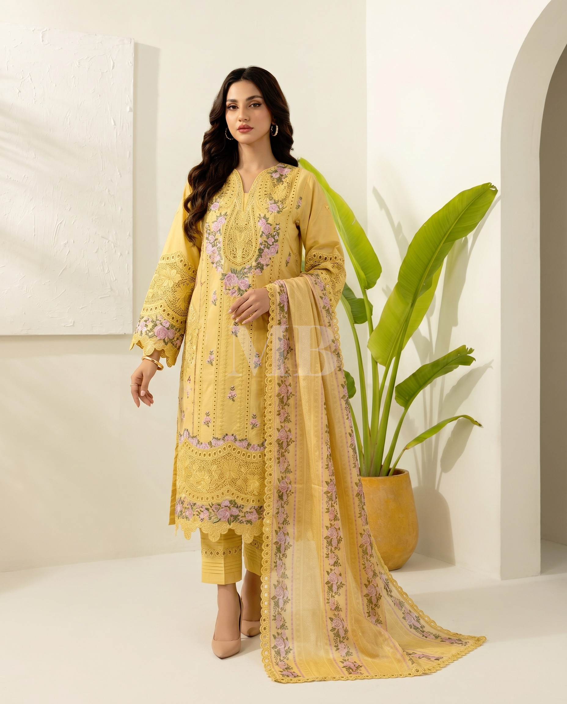 Woman wearing a yellow embroidered traditional outfit with a plant in the background