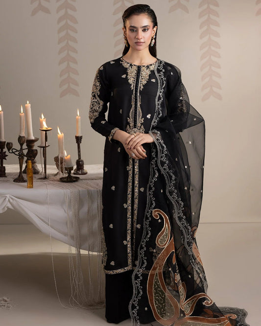 Woman in a black embroidered outfit standing in front of a decorated table with candles.