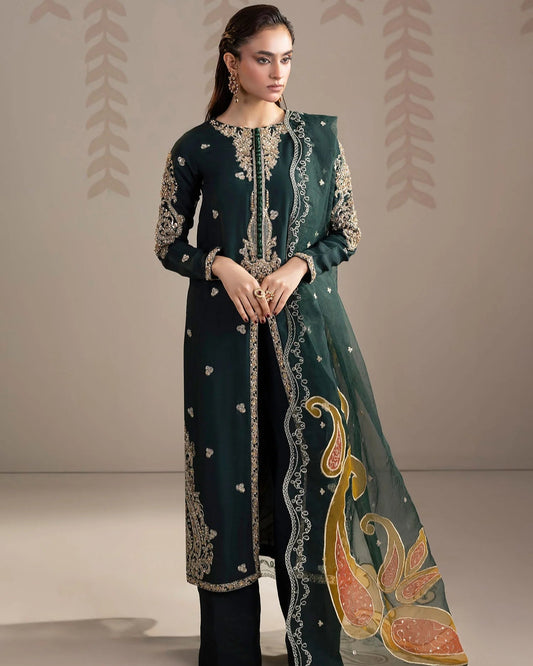 Woman wearing a dark green embroidered outfit with a matching dupatta on a beige background